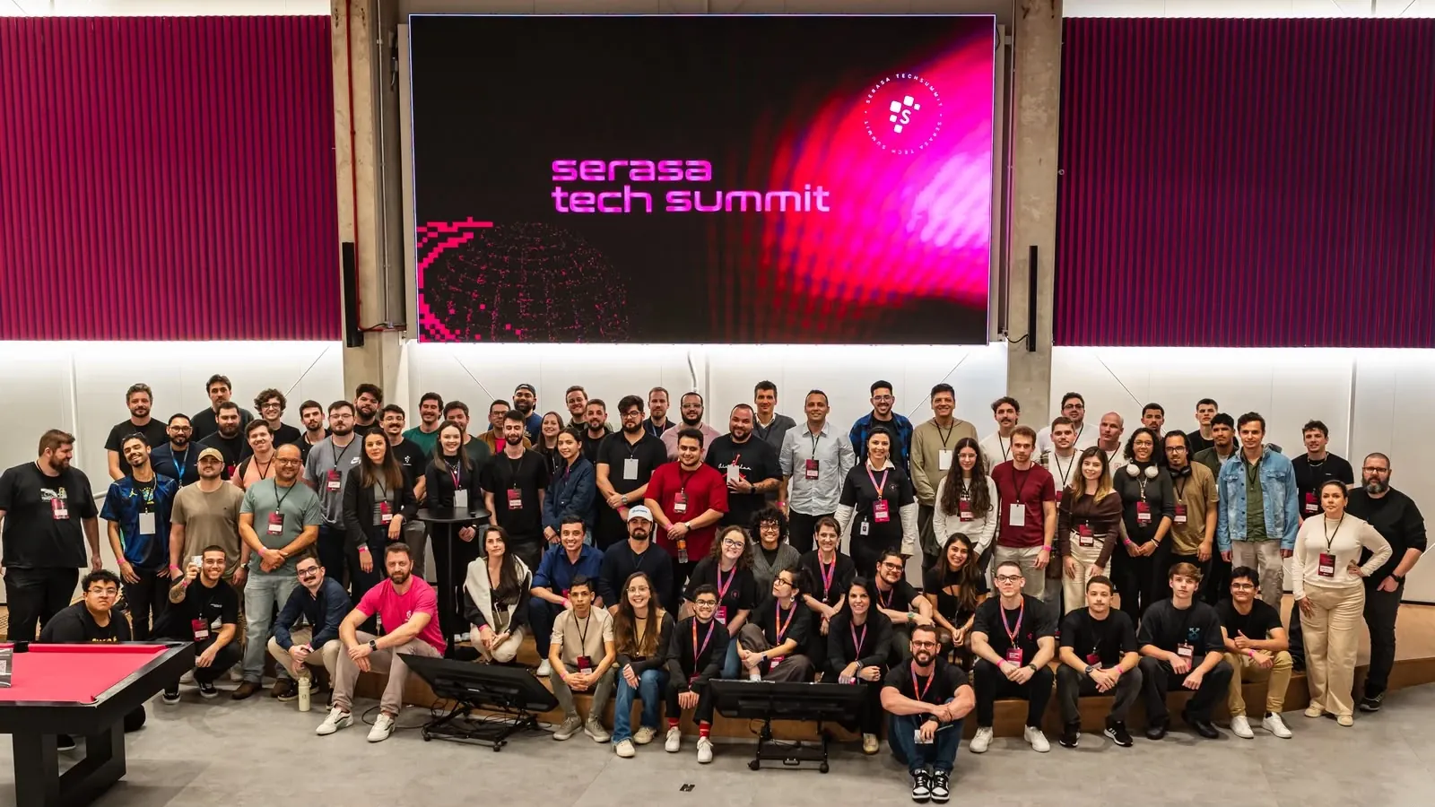 Participantes do Serasa Tech Summit Blumenau reunidos para a foto oficial, em frente ao telão com o nome do evento